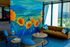 Vibrant lounge area featuring a striking mural of orange poppies and lush landscapes, complemented by modern furniture and large windows inviting natural light.