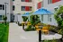 Chic outdoor seating area with vibrant yellow chairs and blue umbrellas, surrounded by lush greenery in a modern apartment complex.