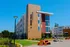 Contemporary apartment building at 2 River Trail, highlighting modern architectural design with vibrant exterior colors and spacious outdoor seating area under a clear blue sky.