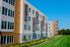 Modern apartment complex exterior with stylish facade details and lush green landscaping under a clear blue sky.