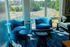 Bright lounge area with stylish blue armchairs, modern side tables, and expansive window views of a scenic outdoor landscape.