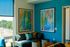 Vibrant living room with colorful forest-themed artwork, modern gray sofa, and large window overlooking a scenic view.