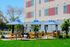 Inviting outdoor seating area with vibrant blue umbrellas and yellow chairs on a sunny day, set against a modern apartment backdrop with lush greenery.