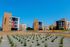 Modern apartment complex with striking architecture, featuring multiple four-story buildings and well-maintained landscaping under a bright blue sky.