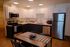 Modern kitchen with sleek white cabinetry, stainless steel appliances, and a stylish dining area with a patterned runner.