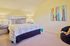 Inviting bedroom with cozy ambiance featuring modern decor, plush bed with patterned bedding, and elegant lighting.