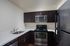 Modern kitchen with sleek dark cabinets, stainless steel appliances, and elegant countertops.