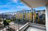 Vibrant cityscape view from a cozy balcony overlooking a modern yellow apartment building against a bright blue sky.