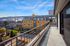 Expansive balcony view with vibrant urban architecture against a scenic bridge backdrop under a clear blue sky.