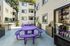 Bright and inviting apartment courtyard with vibrant purple seating, surrounded by modern buildings and lush greenery. Ideal for relaxation and social gatherings.
