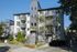 Modern urban apartment building with bright exterior, private balconies, and lush landscaping, offering a desirable city living experience.