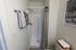 Inviting bathroom with a sleek shower, elegant striped curtain, fluffy towels, and tranquil palm tree artwork.