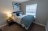 Inviting bedroom with serene beach-themed decor, featuring a cozy bed adorned with plush pillows and a soft, textured throw blanket. Natural light filters through the window, illuminating the room's warm and welcoming atmosphere.