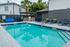 Inviting outdoor pool area with sun loungers, lush palm trees, and a sleek barbecue setup offering a tranquil retreat.