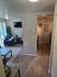 Inviting living room with modern decor, wooden flooring, and a large TV; abundant natural light and cozy seating area for relaxation.