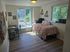 Bright and cozy bedroom with large windows, stylish checkered bedding, and a sleek work desk, bathed in natural light.