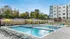 Modern apartment complex featuring a luxurious outdoor pool area with sun loungers, vibrant yellow umbrellas, and a nearby lounge area. Perfect for relaxation and entertainment.