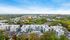 Panoramic aerial view of a modern apartment complex surrounded by lush greenery, showcasing vibrant community living and ample parking.