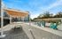 Modern apartment complex with a luxurious outdoor swimming pool, stylish lounge chairs, and a contemporary shaded seating area under a clear blue sky.