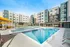 Modern apartment complex featuring a luxurious swimming pool area with sun loungers and shaded seating, perfect for relaxation and outdoor entertainment.