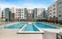 Modern apartment complex with a luxurious outdoor pool and a spacious sun deck featuring stylish lounge chairs, set against a backdrop of elegant architecture.