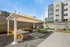 Charming outdoor courtyard featuring a modern pergola, vibrant seating areas, and a sleek grill station in a serene apartment setting.