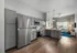 Modern kitchen with sleek gray cabinets, stainless steel appliances, and cozy adjoining living area with large windows.