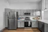 Modern kitchen with sleek stainless steel appliances, elegant gray cabinetry, and bright hardwood flooring. The spacious countertops add to the functionality and style.