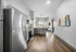 Modern kitchen with stainless steel appliances, sleek cabinetry, and open layout leading to bright living area with large window and stylish decor.