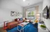 Chic living room with modern art, plush brown sectional, vibrant pillows, and large sunny window on a stylish blue rug.