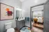 Inviting bathroom with modern vanity, vibrant abstract art, and view into a cozy, sunlit bedroom with stylish decor.