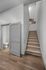 Modern apartment entry featuring sleek wooden flooring, a stylish gray door, and carpeted stairs with vibrant wall art accents.