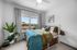 Bright bedroom with cozy bed, modern decor, and large window offering a scenic view. Includes stylish plants and a unique clock.