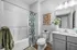 Chic bathroom with modern fixtures, botanical shower curtain, and elegant decor, featuring a stylish countertop plant arrangement.