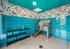 Vibrant pet washing station with turquoise tiles and playful cartoon wallpaper, featuring a stainless steel wash basin and convenient storage shelves.