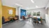 Bright and modern communal room with colorful seating, cozy booths, and a dining area, featuring large windows and artistic decor.