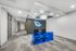 Modern office reception area with a striking blue glass desk, chic chairs, and a glowing leaf wall decoration under stylish lighting.