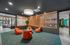 Modern lounge area featuring vibrant orange seating, lush greenery, and stylish wooden partitions creating a cozy ambiance.