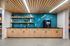 Modern communal kitchen area with sleek wooden cabinets, vibrant blue tile backsplash, and a convenient coffee machine, perfect for social gatherings.