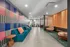 Chic apartment lobby featuring vibrant striped accent wall, modern teal seating with orange cushions, and stylish wooden elements.