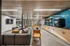 Inviting community lounge showcasing a modern open-plan design with cozy seating, stylish wood accents, a vibrant blue tiled coffee station, and chic yellow dining furniture.
