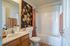 Charming and bright bathroom featuring elegant floral artwork, modern sink with storage, cozy towels, and a pristine shower area.