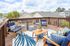 Charming rooftop patio with cozy blue chairs, vibrant patterned cushions, and a stylish outdoor rug, perfect for relaxation and entertaining under the open sky.