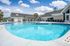 Inviting apartment community pool with modern lounge seating under a clear blue sky, perfect for relaxation and leisure.