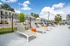 Inviting apartment community with modern lounge chairs by a sparkling pool under a vibrant blue sky.