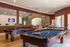 Inviting recreational room featuring two elegant billiards tables, a vibrant seating area, and large windows for ample natural light.