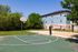 Inviting outdoor amenities with a basketball court, sand volleyball court, and lush greenery surrounding a modern apartment building.