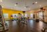 Bright and spacious fitness center featuring modern exercise equipment, vibrant yellow accent wall, and large windows for natural light.