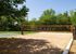 Inviting outdoor sand volleyball court and basketball hoop surrounded by lush greenery, perfect for sports enthusiasts.
