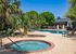 Charming outdoor area featuring a serene pool and hot tub surrounded by lush palm trees and cozy seating, perfect for relaxation and leisure.